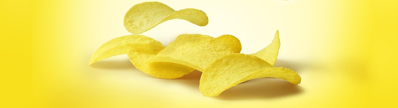 Potato chips gently falling on a yellow background.